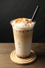 Tasty milk bubble tea in plastic cup on wooden table, closeup
