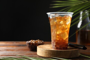 Tasty iced bubble tea and ingredients on wooden table. Space for text