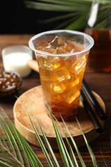 Tasty iced bubble tea and ingredients on wooden table