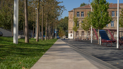 Naklejka premium Urban Park with Pathway, Trees, and Historic Building