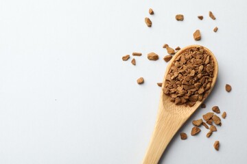 Spoon with granulated instant coffee on white background, top view. Space for text