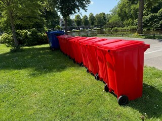 Many color trash bins on green grass in park, space for text