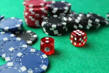 Casino chips and dice on green table, closeup