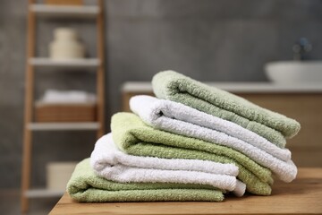 Fresh terry towels on wooden table in bathroom, closeup. Space for text