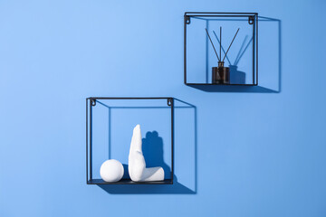 Metal shelves with stylish decor on blue background