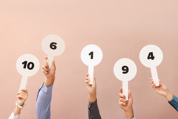 Panel of judges voting with score signs on beige background, closeup