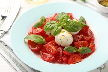 Tasty salad Caprese with mozzarella, tomatoes, basil and spices on table, closeup