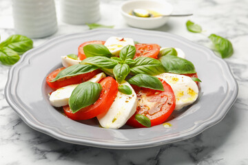 Tasty salad Caprese with mozzarella, tomatoes, basil and spices on white marble table, closeup