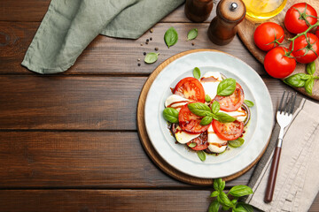 Tasty salad Caprese served with balsamic vinegar on wooden table, flat lay. Space for text