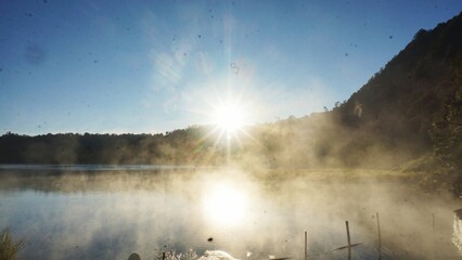 Sunrise at Talaga Bodas, Garut, Indonesia, reveals a mystical scene with fog drifting above the crater lake and the sunlight breaking through the misty morning