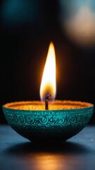 Teal Diya with Bright Flame Against Dark Background