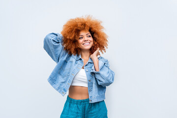 Young stylish latina woman model in denim jacket holding curly afro hairstyle, standing at isolated...