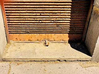 The sun is shining on a rusty shutter. Shadow.
