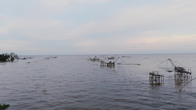 Traditional bamboo fishing nets in a calm lake at dusk. Peaceful rural scene capturing local fishing lifestyle in Southeast Asia. Ideal for travel, nature, and cultural content.