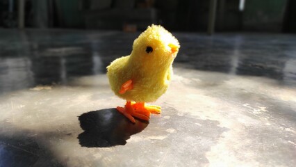 Close Up of a Yellow Toy Chicken with Orange Legs and Beak on Gray Surface