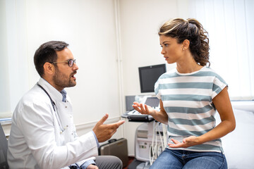 Obraz premium Doctor and female patient having a serious discussion during a medical consultation in a bright, modern exam room.