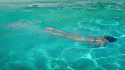 Slow motion of woman diving and swimming across pool, emerging smiling on ladder – joyful summer lifestyle in 4K