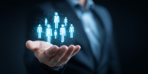 Businessman holding a group of glowing human icons, symbolizing team management or social networking.