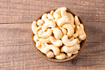 Organic roasted cashew nuts in a wooden bowl. Top view. 