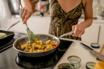 Woman Cooking in a Bright Kitchen While Preparing a Fresh Vegetable Dish in a Pan