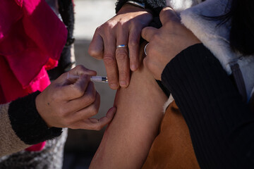 Closeup of a nurse's hand applying a vaccine with a syringe.
