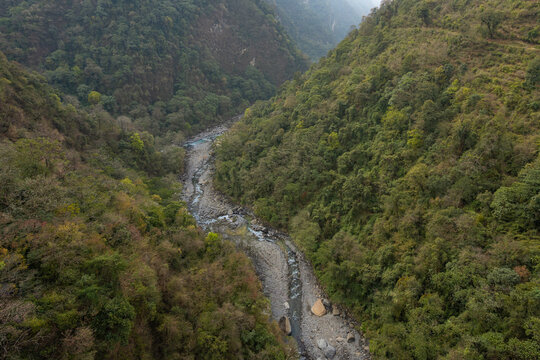 Mountain valley hiking trail from Tadapani to Jhinu Danda in Nepal - Scenic Himalayan landscape with rope bridges and wild river.