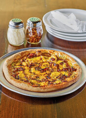 uncut bbq chicken pizza with grated parmesan cheese and red pepper