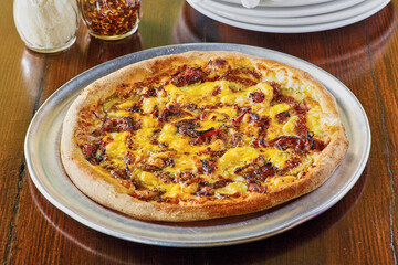 uncut bbq chicken pizza with grated parmesan cheese and red pepper