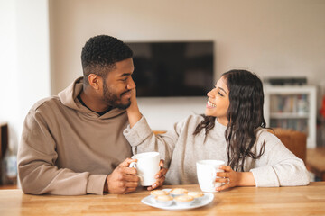 Smiling couple enjoying coffee and cookies in a cozy living room during a relaxed afternoon together