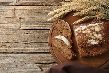 Pieces of fresh rye bread and spikes on wooden table, flat lay. Space for text