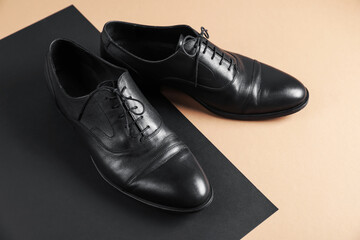 Pair of black leather shoes on color background, closeup