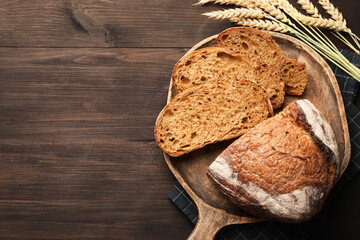 Naklejka premium Pieces of fresh bread and spikes on wooden table, flat lay. Space for text