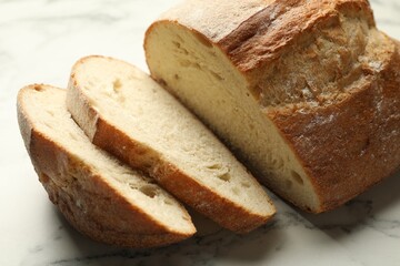Pieces of fresh bread on white marble table, closeup