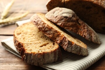 Pieces of fresh bread and spikes on wooden table, closeup