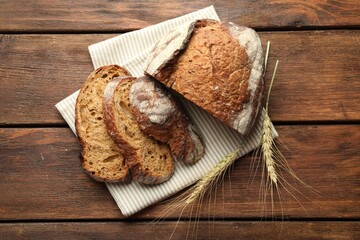 Pieces of fresh bread and spikes on wooden table, flat lay