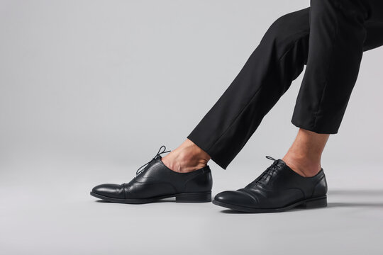 Man wearing pair of black leather shoes on light background, closeup. Space for text - Powered by Adobe