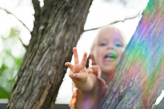 Young Aussie kid playing up a tree holding up three fingers