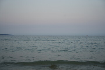 Calm sea with soft pastel sky at sunset or sunrise. Minimalist seascape with gentle waves and a clean horizon line.