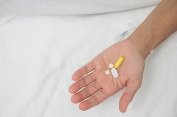 Patient showing pills in his hand while lying in hospital bed, recovering after surgery