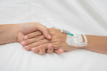 Doctor is holding the hand of a patient with iv drip, giving support during treatment