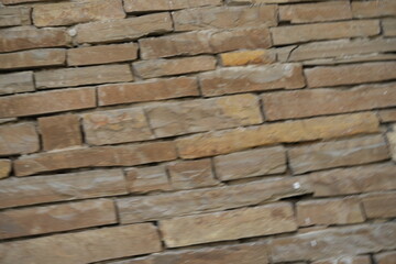 Fototapeta premium Natural sandstone wall texture with irregular horizontal layers and warm earthy tones. Rough stacked stone surface ideal for architectural backgrounds and 3D materials.