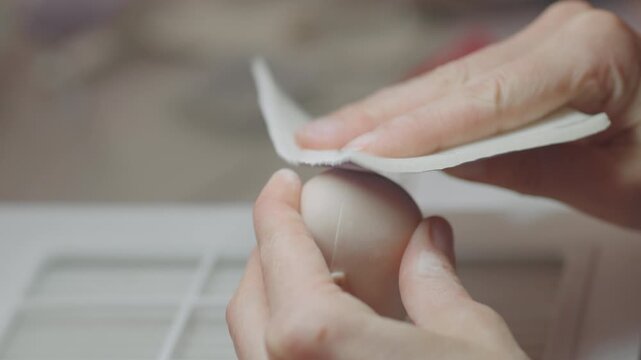 Closeup of artist sanding silicone doll head using cloth to smooth surface and refine shape during preparation process before detailing in workshop