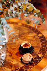 Close-up of a cup of aromatic cappuccino with a cupcake stands on a wooden table in the rays of the sunset. A delicious hot drink with dessert in a coffee shop. Food and drink concept.