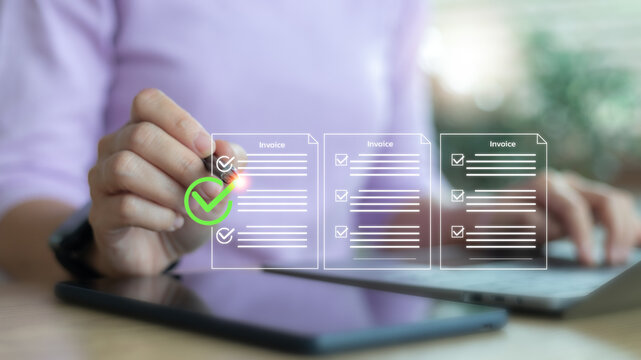 Hand using a stylus to mark completed invoices on a digital screen, symbolizing online billing, invoice processing, payment approval, and a paperless finance system.