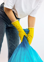 A woman with a blue trash bag poses on a white background