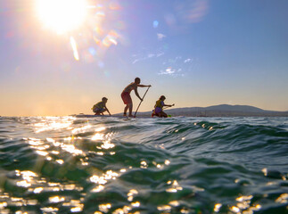 family with kids  riding  on sup surfing in the sea at summer day.