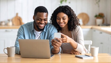 Couple using laptop and phone in kitchen