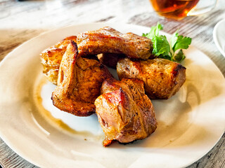 Savory grilled meat served on a white plate with fresh herbs in a casual dining setting
