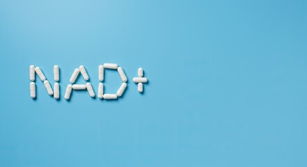 NAD+ sign made from white supplement capsules with bottle on blue background with copy space. Nicotinamide adenine dinucleotide for anti-aging and longevity.