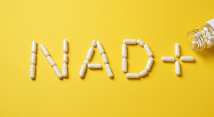 NAD+ sign made from white supplement capsules with bottle on yellow background with copy space. Nicotinamide adenine dinucleotide for anti-aging and longevity.